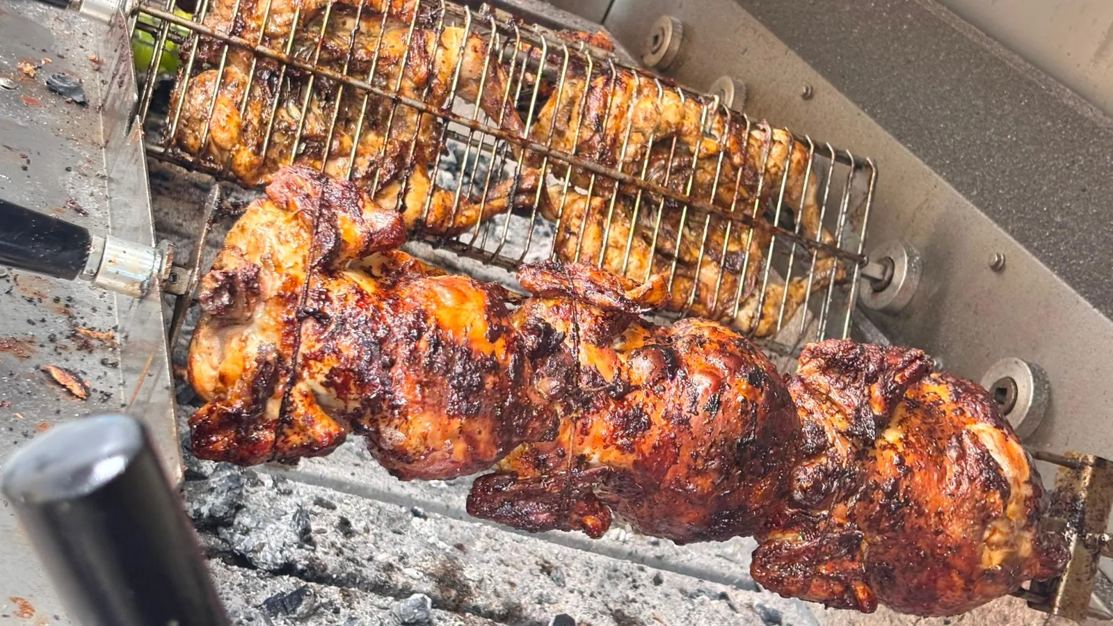 Pollos girando sobre brasas de carbón